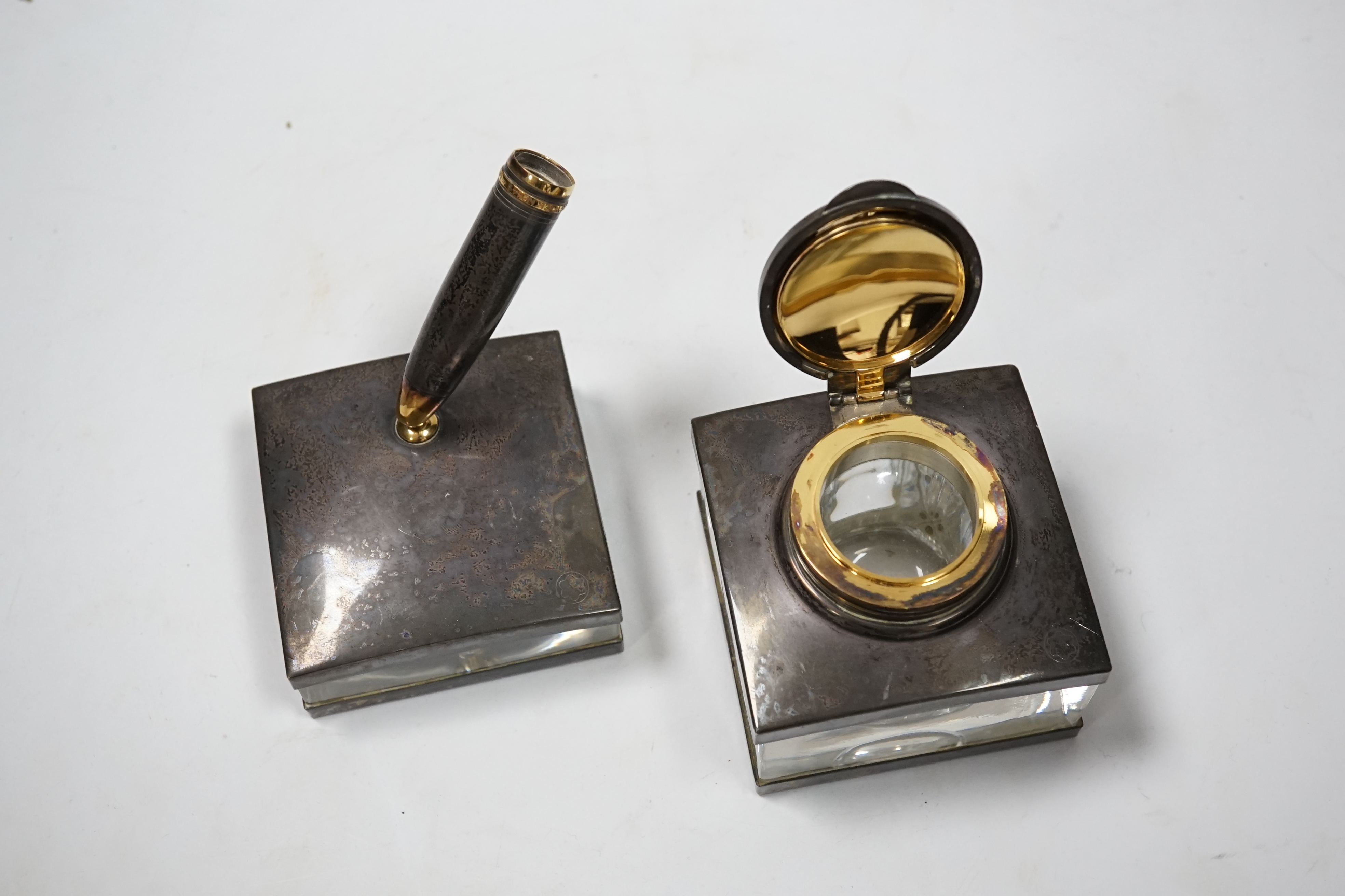 A Montblanc three piece German silver and glass desk set comprising pen stand, inkwell and blotter, each glass mounted, silver engraved with the Montblanc logo